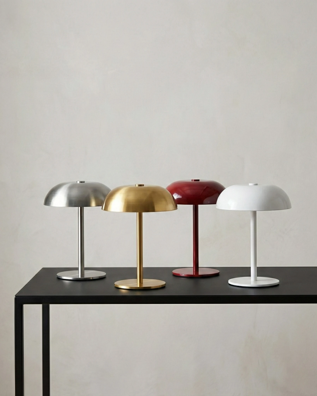Set of four cordless mushroom lamps LUMA No.02 in silver, gold, red and white on a black metal console table