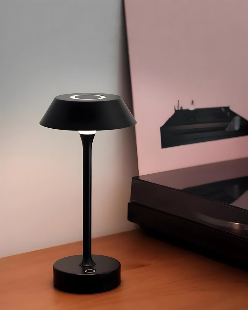 Cordless mushroom lamp CIMA No.01 in black lit on a wooden surface beside a turntable in a pink-lit room