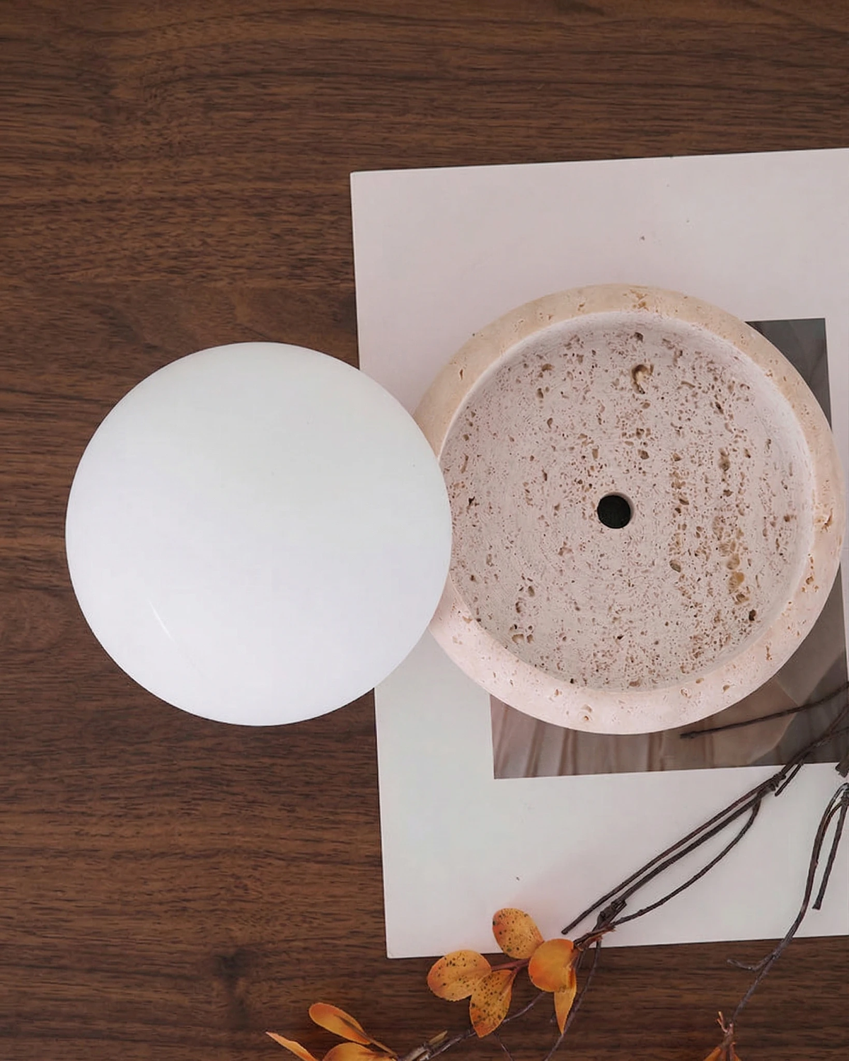 Close-up from above of the LUCE No.01 cordless outdoor table lamp with the opal dome set beside its travertine base