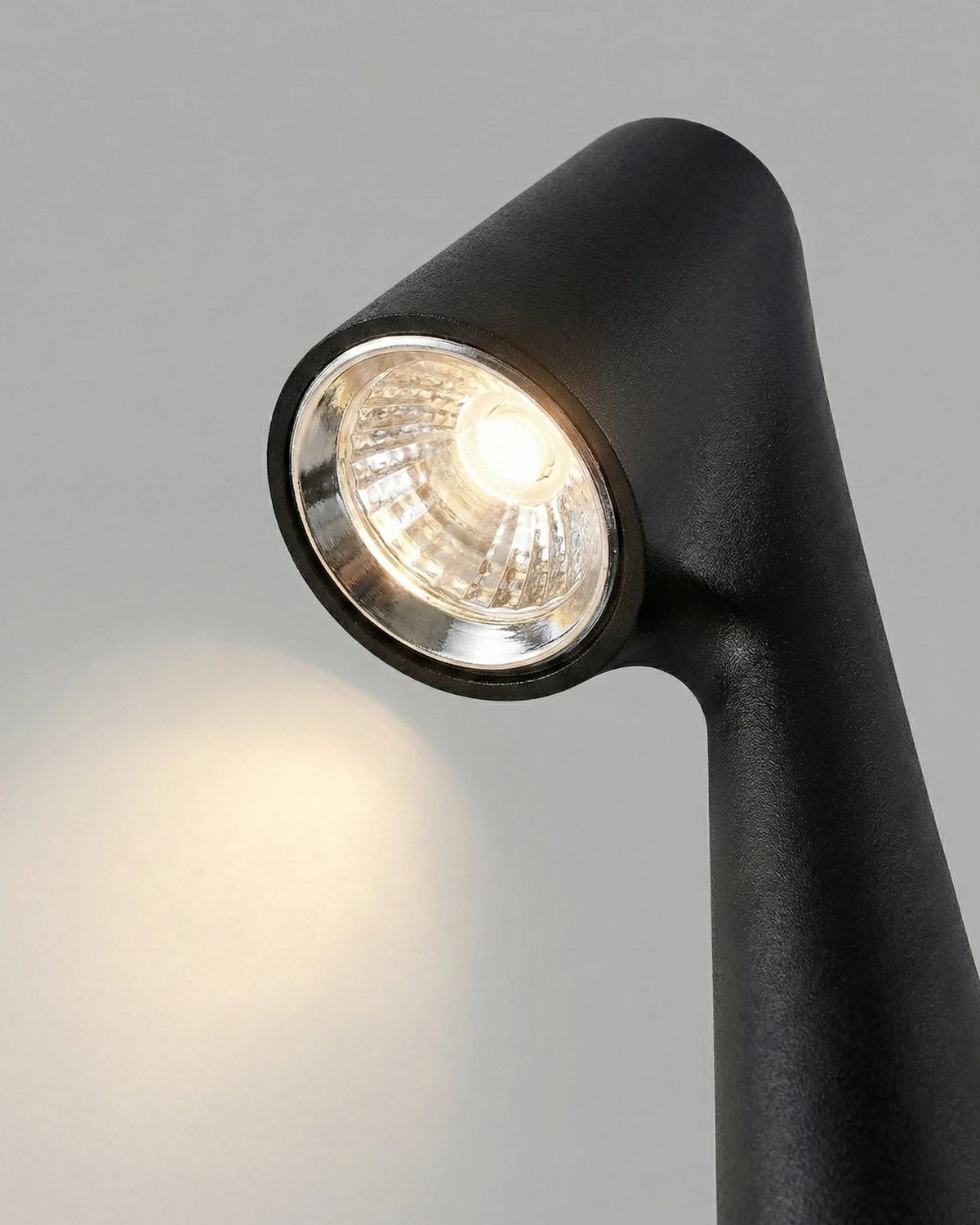 Close-up of the black angled head and LED lens of the TRIESTE No.01 cordless reading lamp, switched on