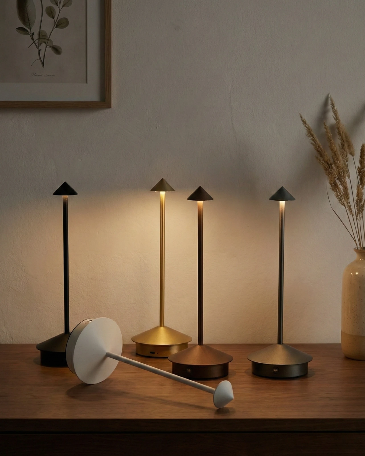 Four cordless table lamps FERRARA No.01 in mixed metallic finishes on a walnut sideboard, one lying on its side