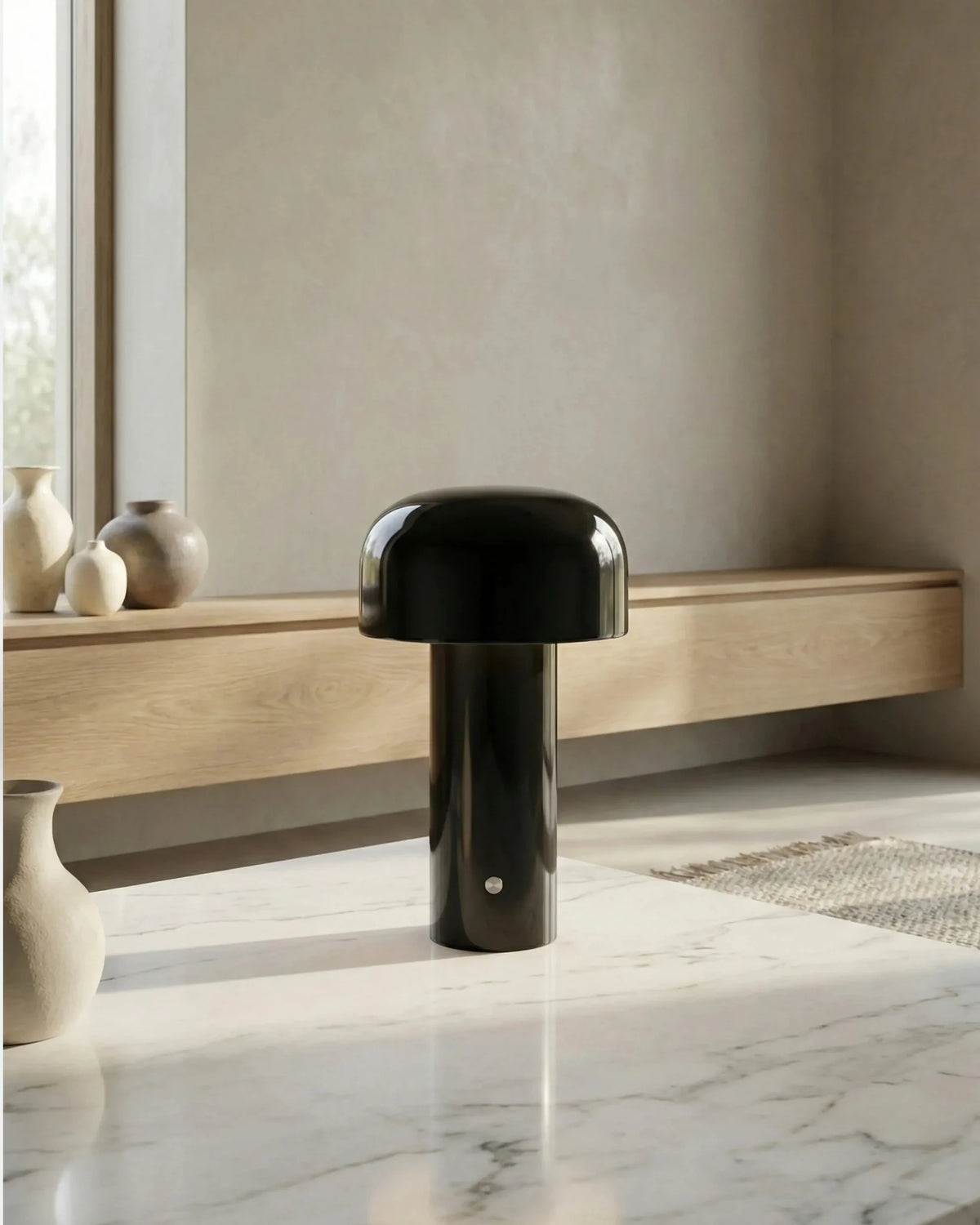 Cordless table lamp DOLCE No.01 in deep black standing on a marble surface beside ceramic vases
