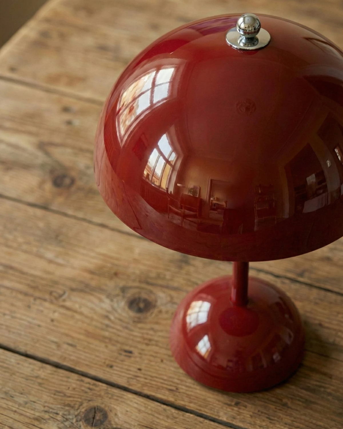 Close-up of the glossy wine red dome and stem of the DOMA No.02 cordless table lamp standing on a wooden floor