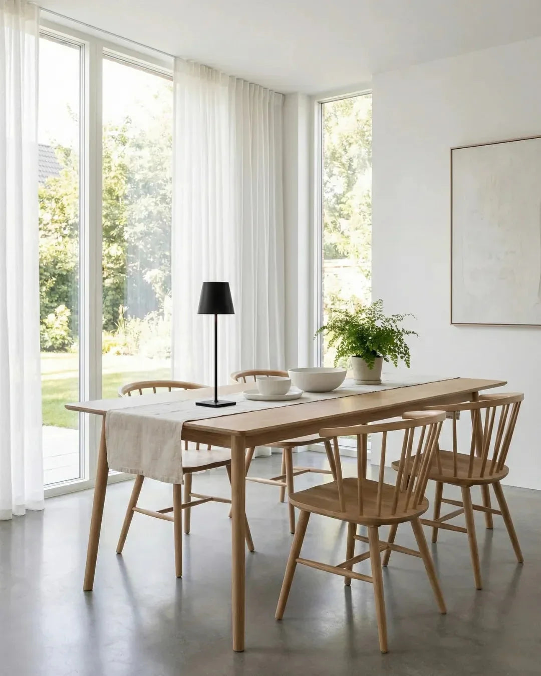 Cordless table lamp FOGGIA No.01 in black standing on a light oak dining table in a bright white room