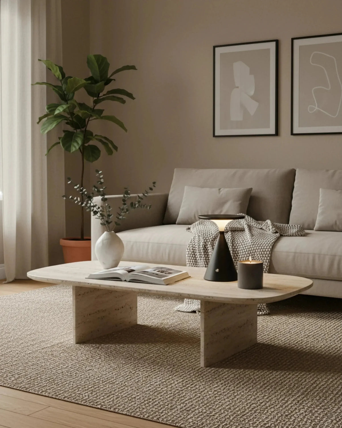 Cordless table lamp SOSTA No.01 in matte black lit on a travertine coffee table in front of a grey sofa