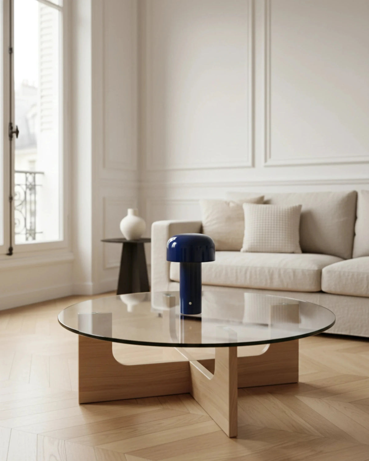 Cordless table lamp DOLCE No.01 in royal blue on a small side table beside a white sofa in a bright living room