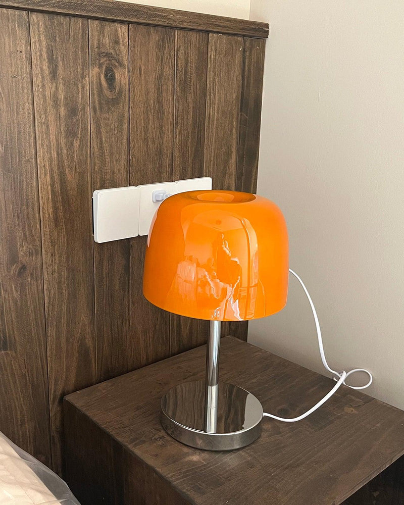 Glass table lamp VENEZIA No.01 with orange shade on a dark wood nightstand against a wooden headboard