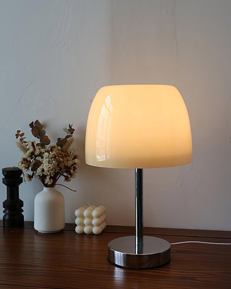 Glass table lamp VENEZIA No.01 switched on, cream shade glowing warmly on a wood console with vases and candle holders