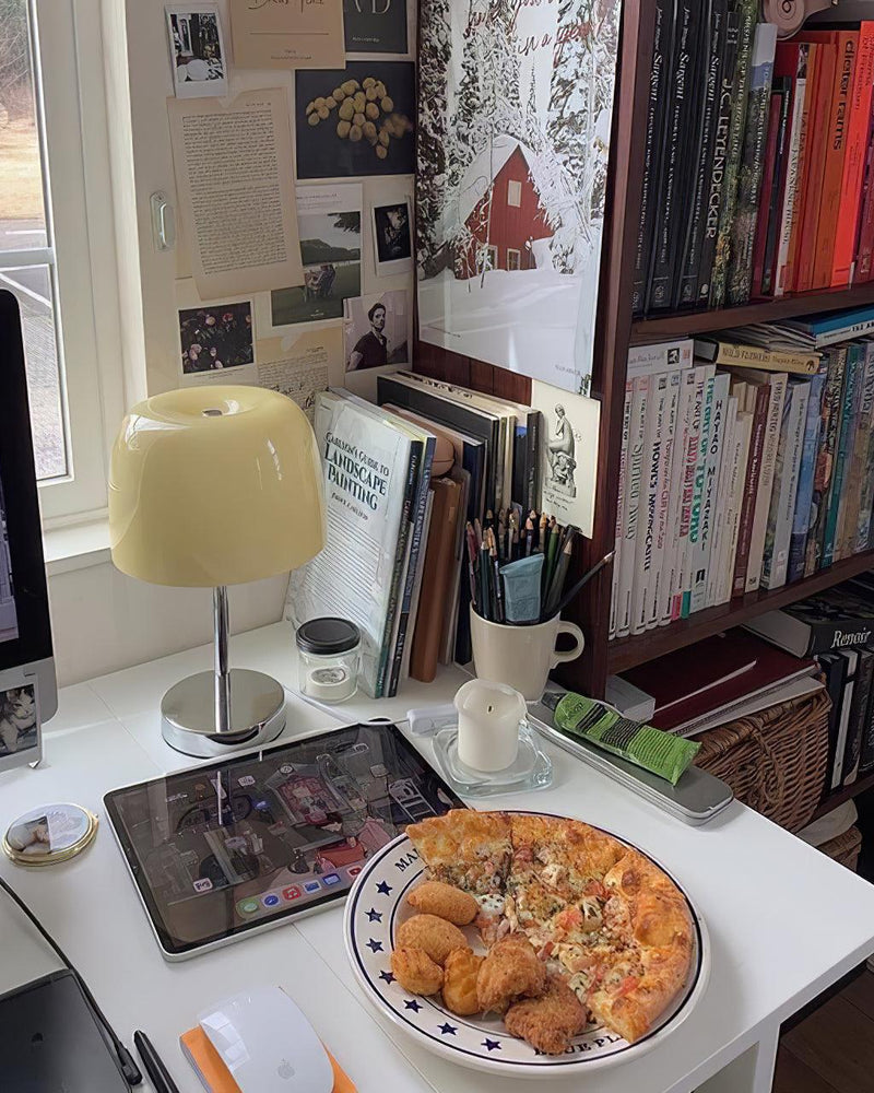 Glass table lamp VENEZIA No.01 with cream shade on a white desk with a tablet, books and a plate of pastries