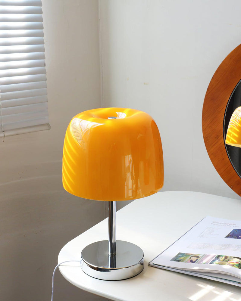 Glass table lamp VENEZIA No.01 with yellow shade, unlit, on a white table by window blinds and a round mirror