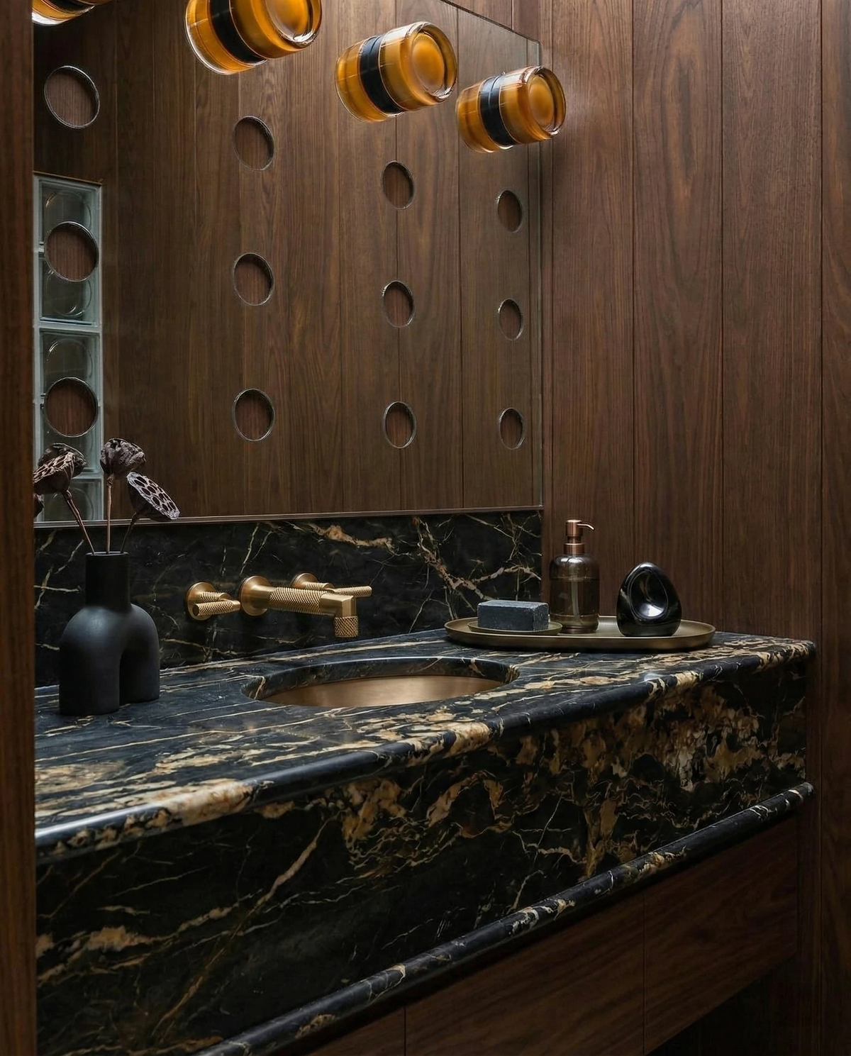 Glass wall sconce HALO No.08, amber units lit on a walnut panel above a black marble bathroom vanity