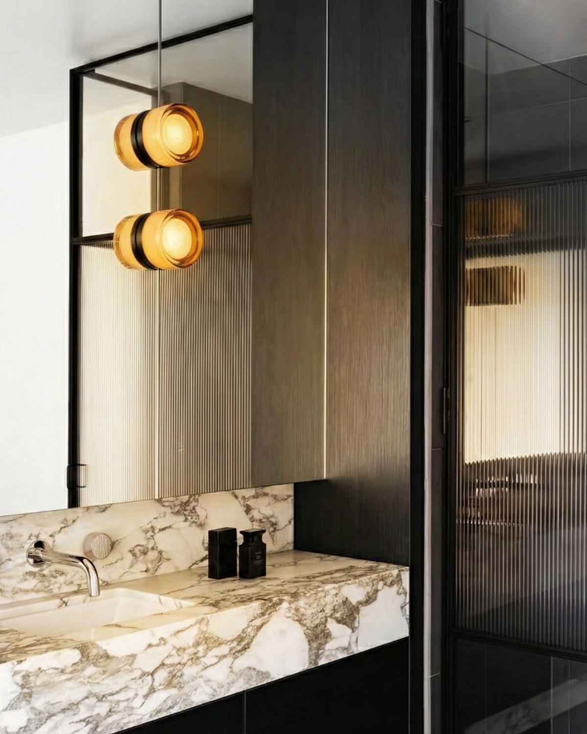 Glass wall sconce HALO No.08, two amber units switched on beside a marble bathroom vanity