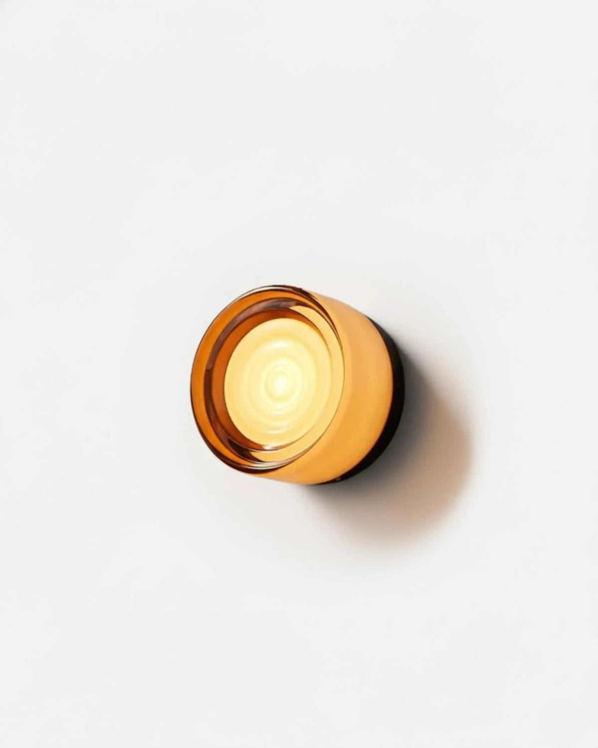 Glass wall sconce HALO No.08 in Amber Echo, rippled amber glass with a black rim, switched on