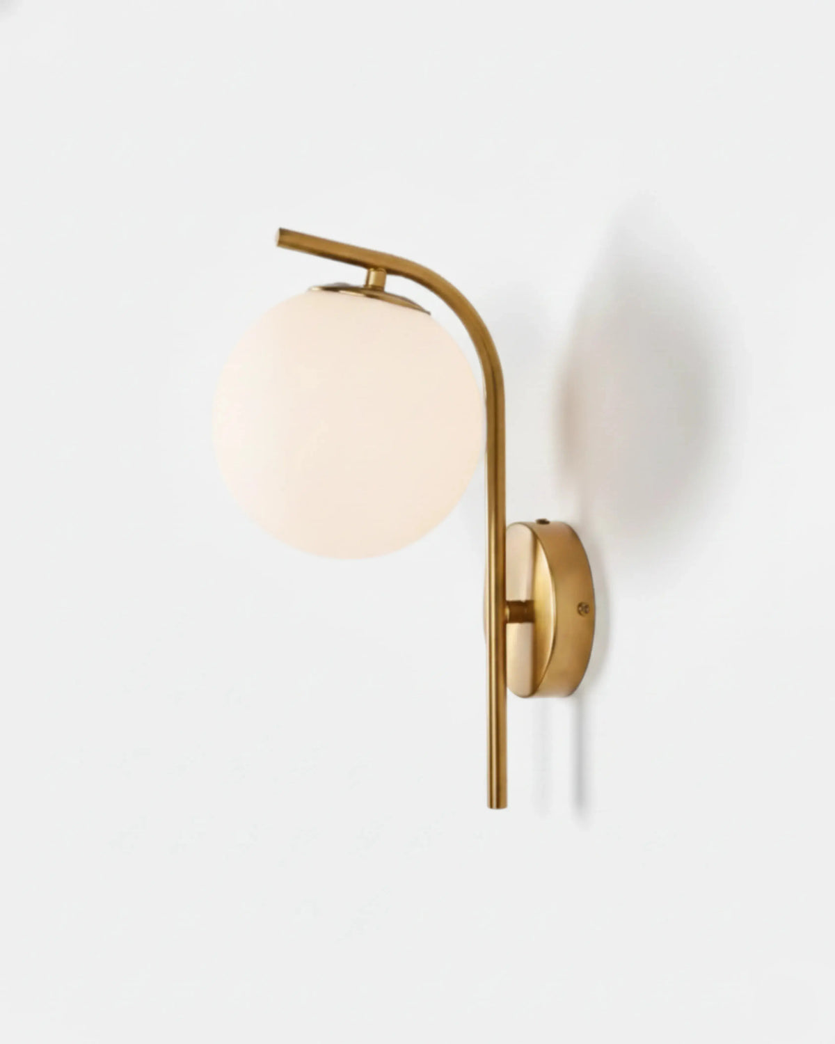 Globe wall sconce MIRA No.01 in Brushed Brass, opal glass globe hanging from an arched brass arm