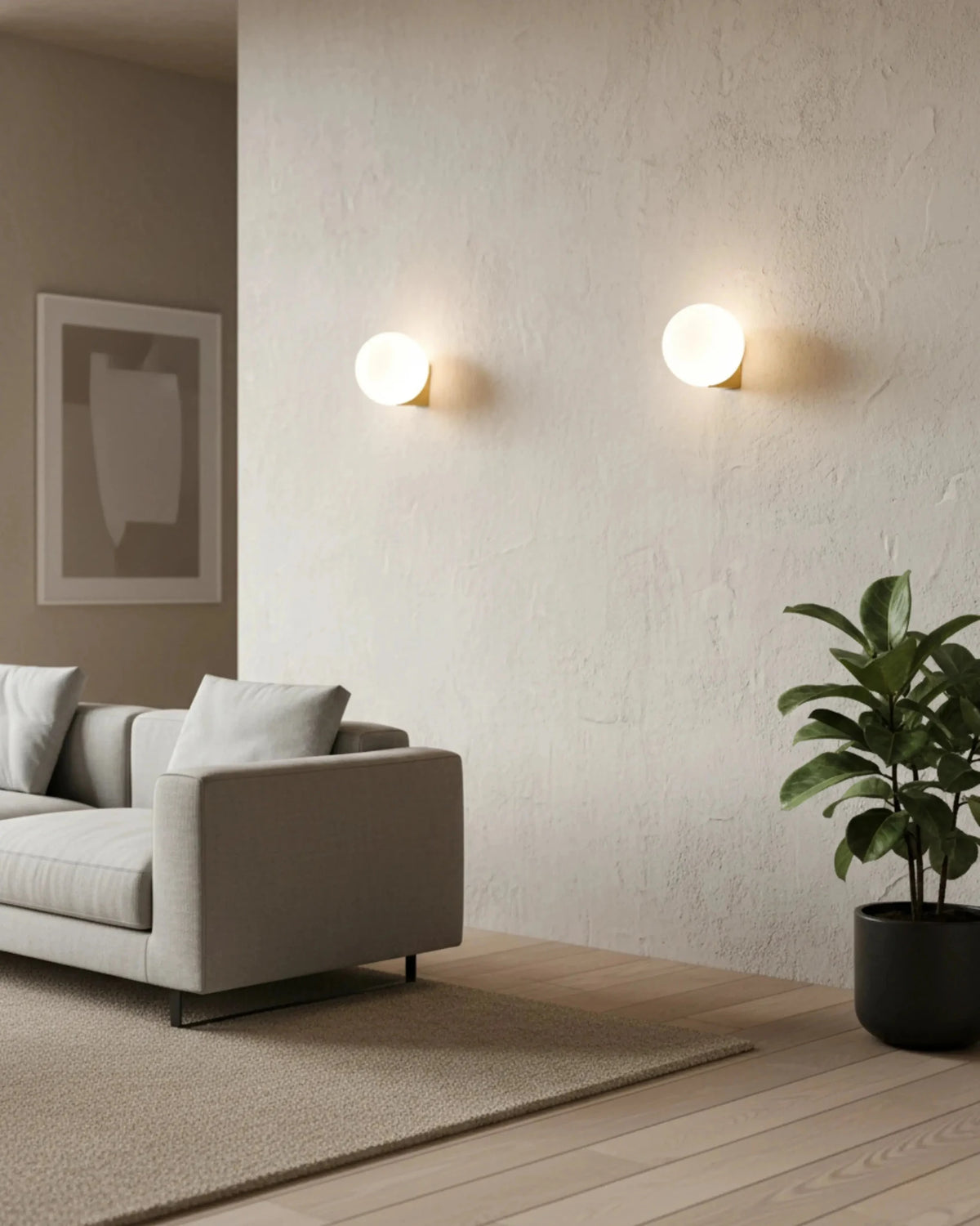 Two globe wall sconces AURA No.03 single lit on a wall above a grey sofa with a plant in a living room