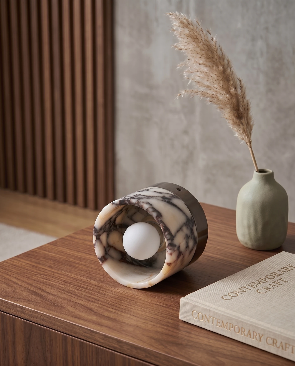 Marble flush mount ceiling light NERA No.06 lying on its side on a walnut sideboard beside a vase of pampas grass