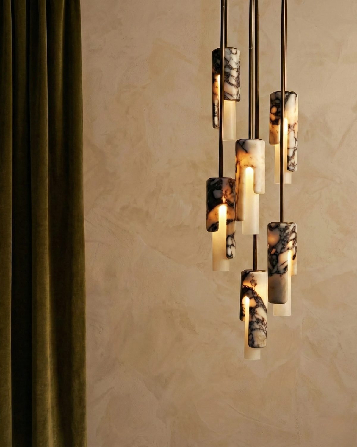 Marble pendant light PALERMO No.01, six cylinders lit at staggered heights next to an olive velvet curtain
