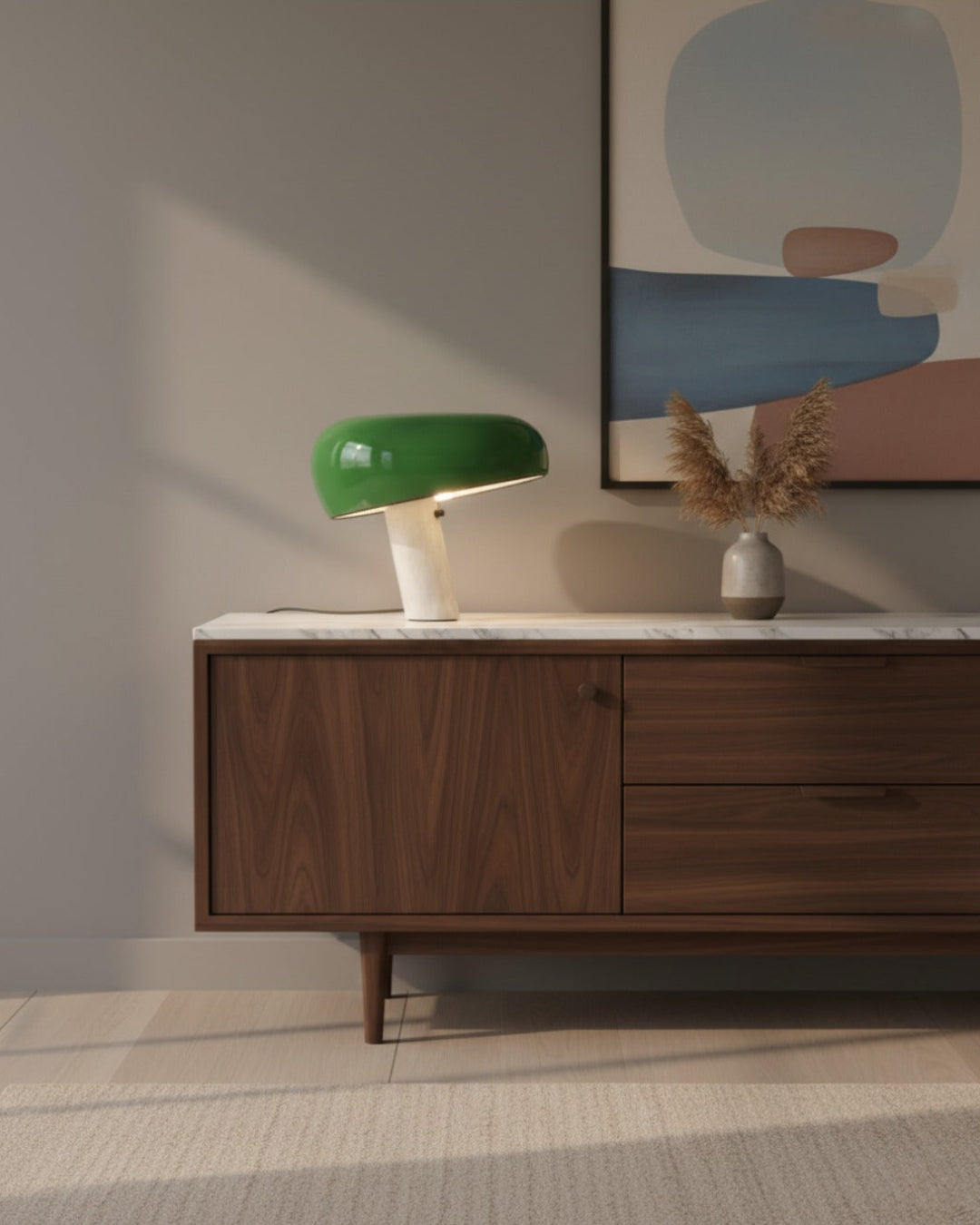 Marble table lamp BRUNO No.01 in green switched on atop a marble-topped walnut sideboard below an abstract painting