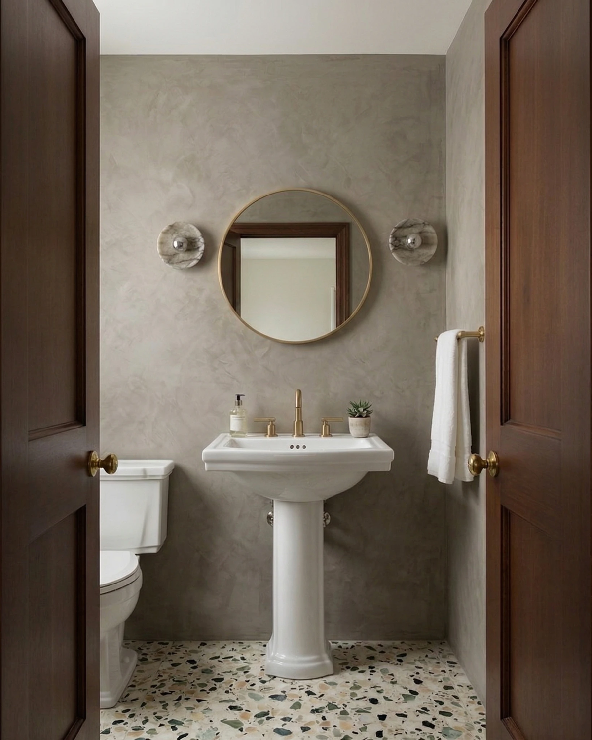 Two marble wall sconces LATTE No.01 in chrome flanking a round mirror above a pedestal sink in a powder room