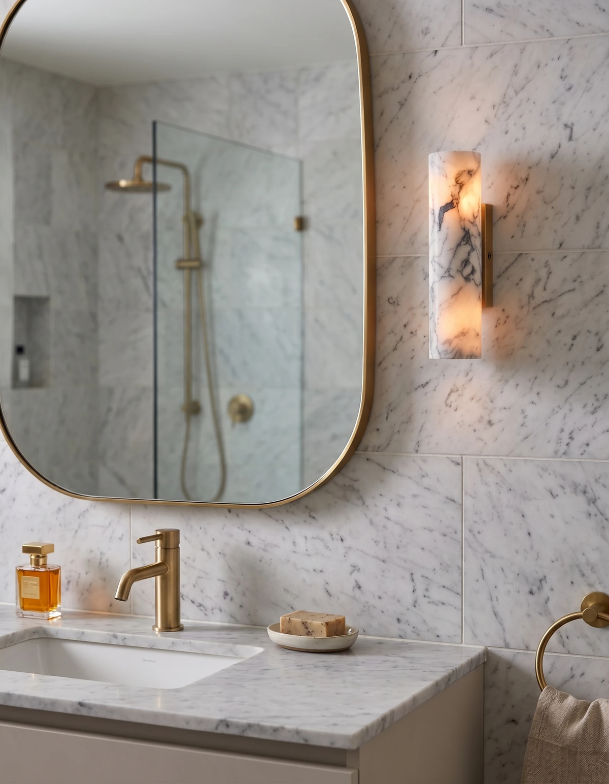 Marble wall sconce PORTORO No.01 switched on beside a rounded mirror over a marble sink with brass tap
