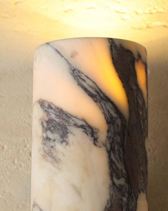 Close-up of the lit viola calacatta marble cylinder of the marble wall sconce PORTORO No.01 with purple veins