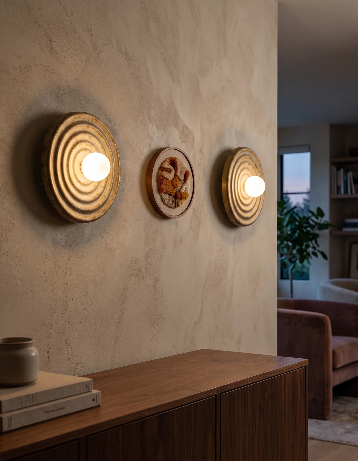 Two modern wall sconces ANIMA No.01 in antique white lit on a plaster wall above a walnut sideboard
