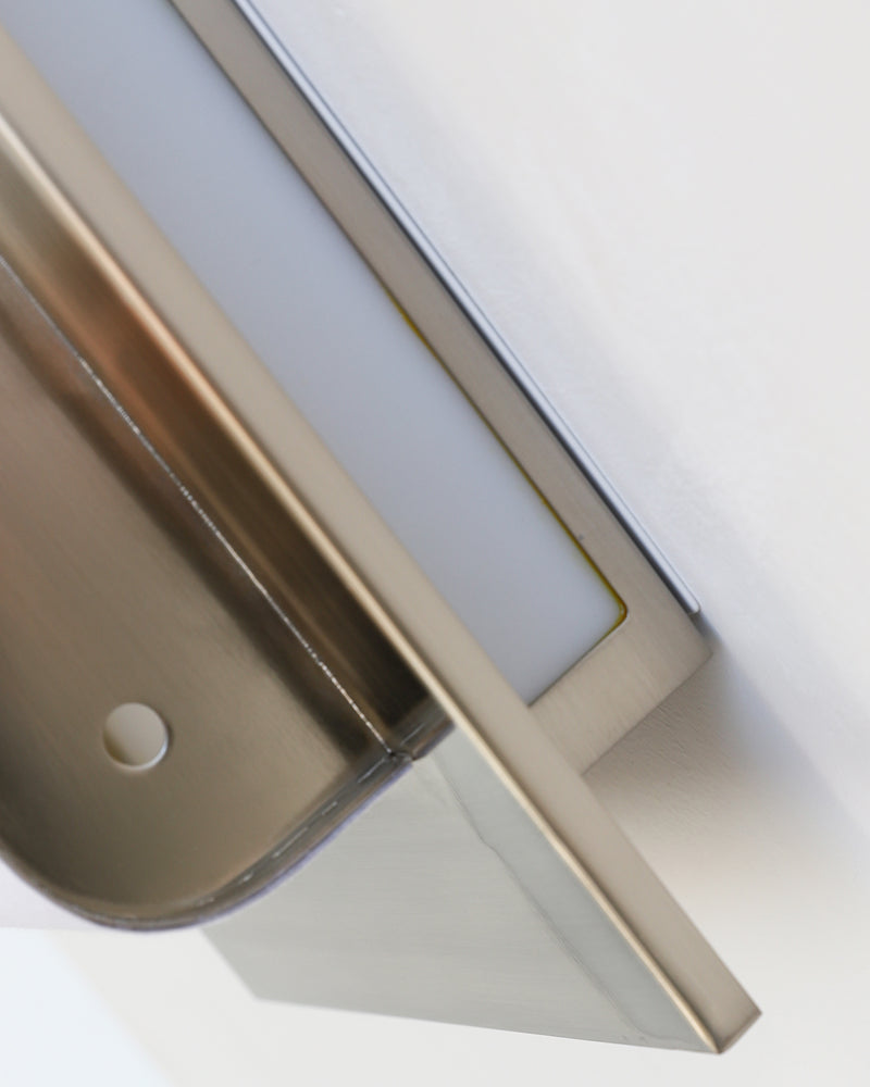 Close-up of the chrome frame corner and acrylic panel of the MILANO No.01 modern wall sconce, unlit