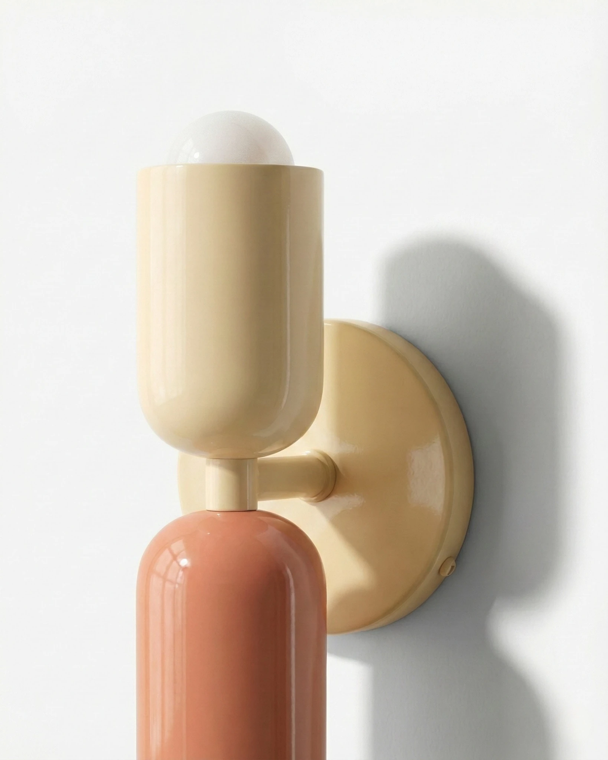 Close-up of the modern wall sconce MURO No.02 in sand and pink, capsule joint and round cream backplate, unlit