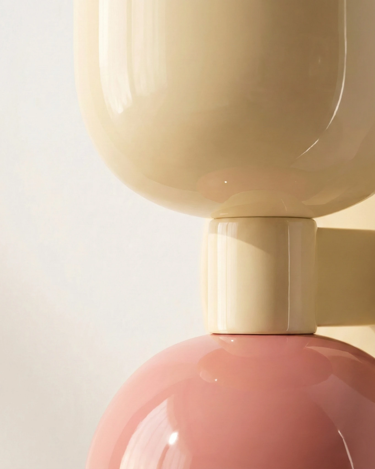 Close-up of the glossy cream and pink capsule shades meeting at the center joint of the TORINO No.01 modern wall sconce