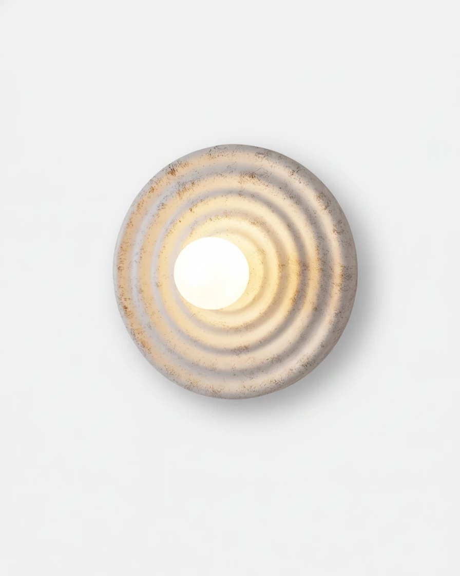 Modern wall sconce ANIMA No.01, rippled antique white resin disc with a glowing center globe on a white wall