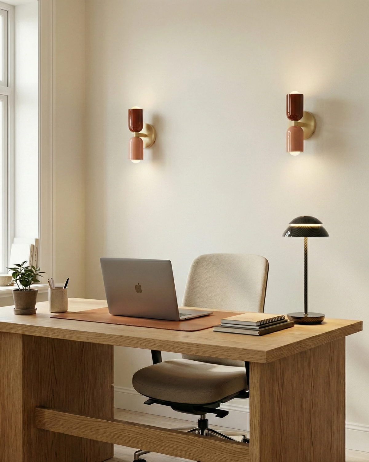 Two modern wall sconces MURO No.02 in crimson and pink, lit on a home office wall above an oak desk with a laptop