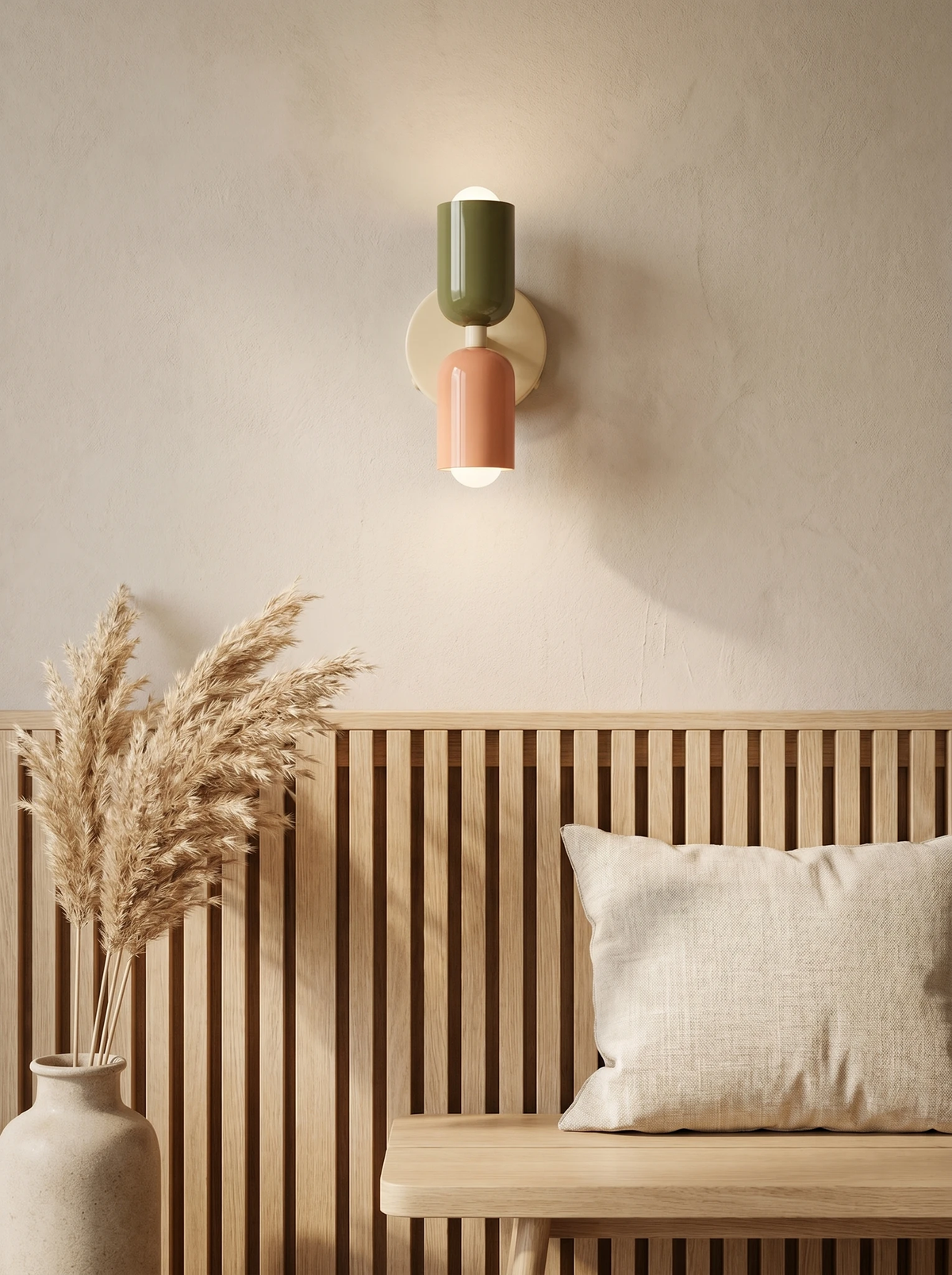 Modern wall sconce MURO No.02 in sage and pink, lit above a wood slat wall bench with a linen cushion and dried grass