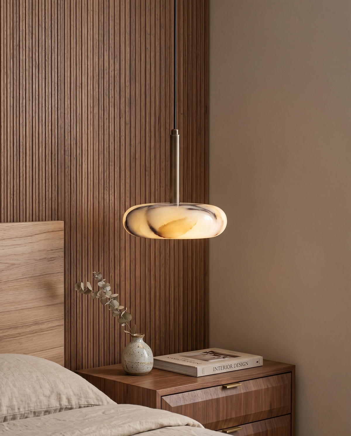 Onyx pendant light TIBER No.01 single, veined stone disc lit beside a slatted walnut headboard above a nightstand