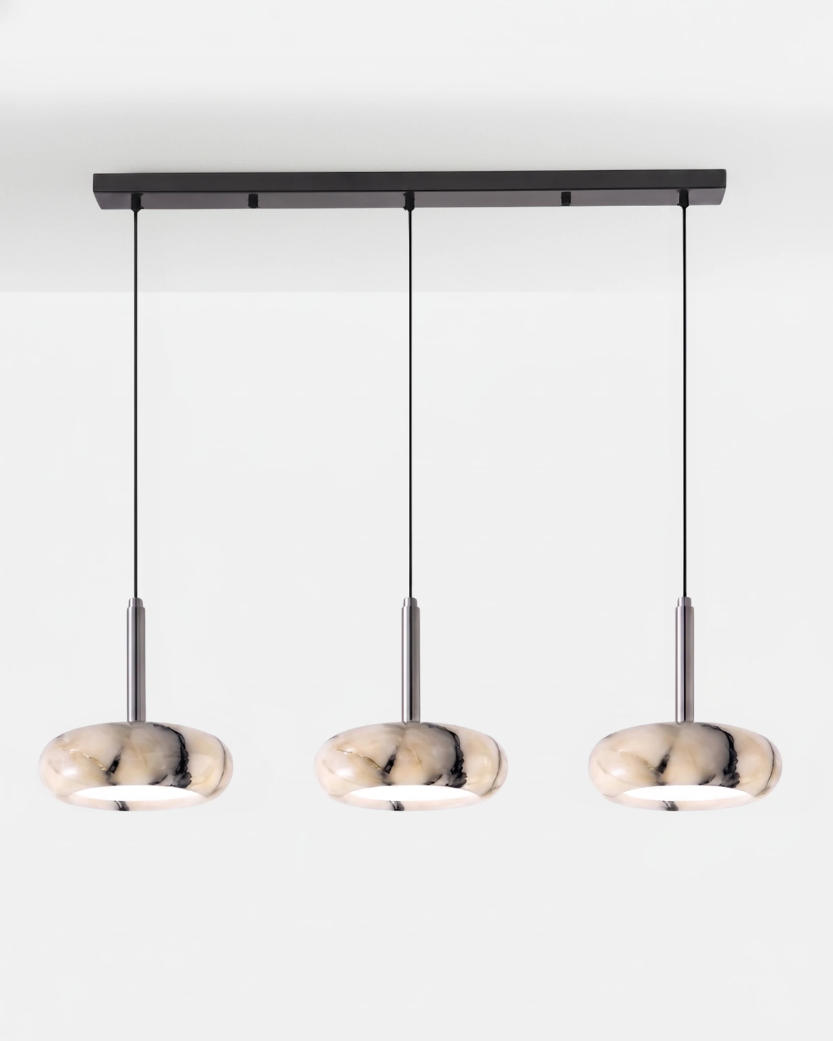 Onyx pendant light TIBER No.01 Linear Three-Head, three lit veined onyx discs on a black linear ceiling bar