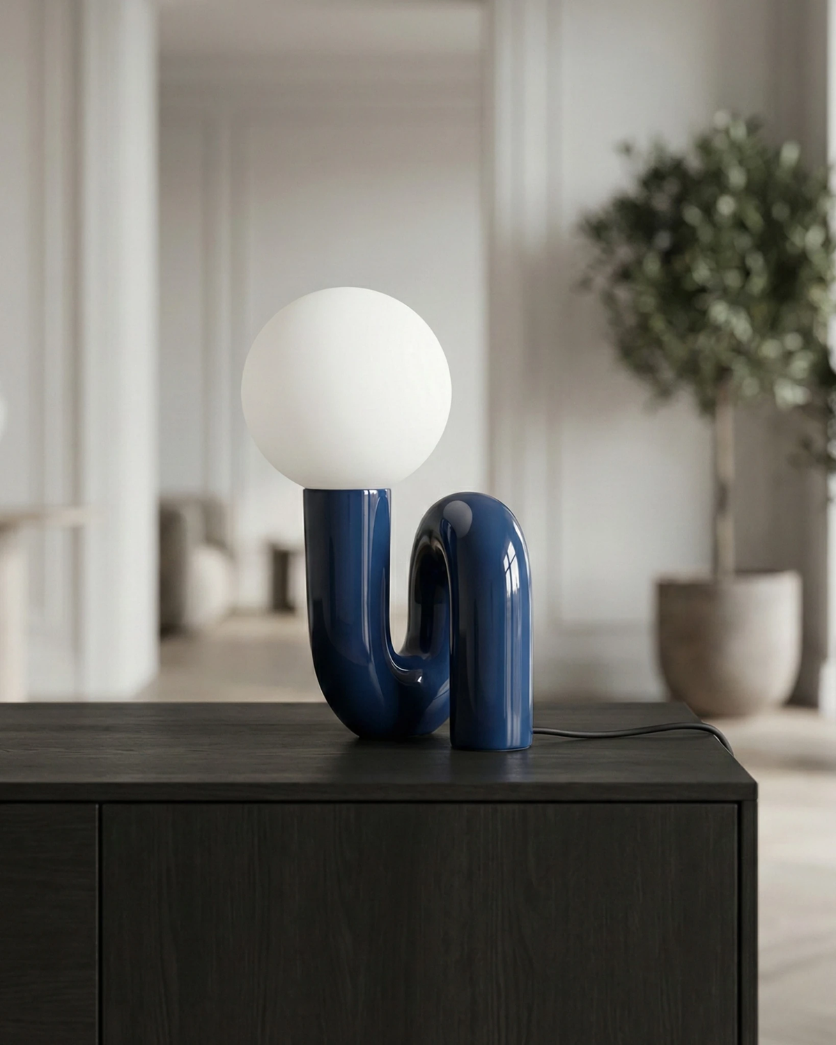 Opal globe table lamp VICO No.01 in french blue lit on a black sideboard in a bright room