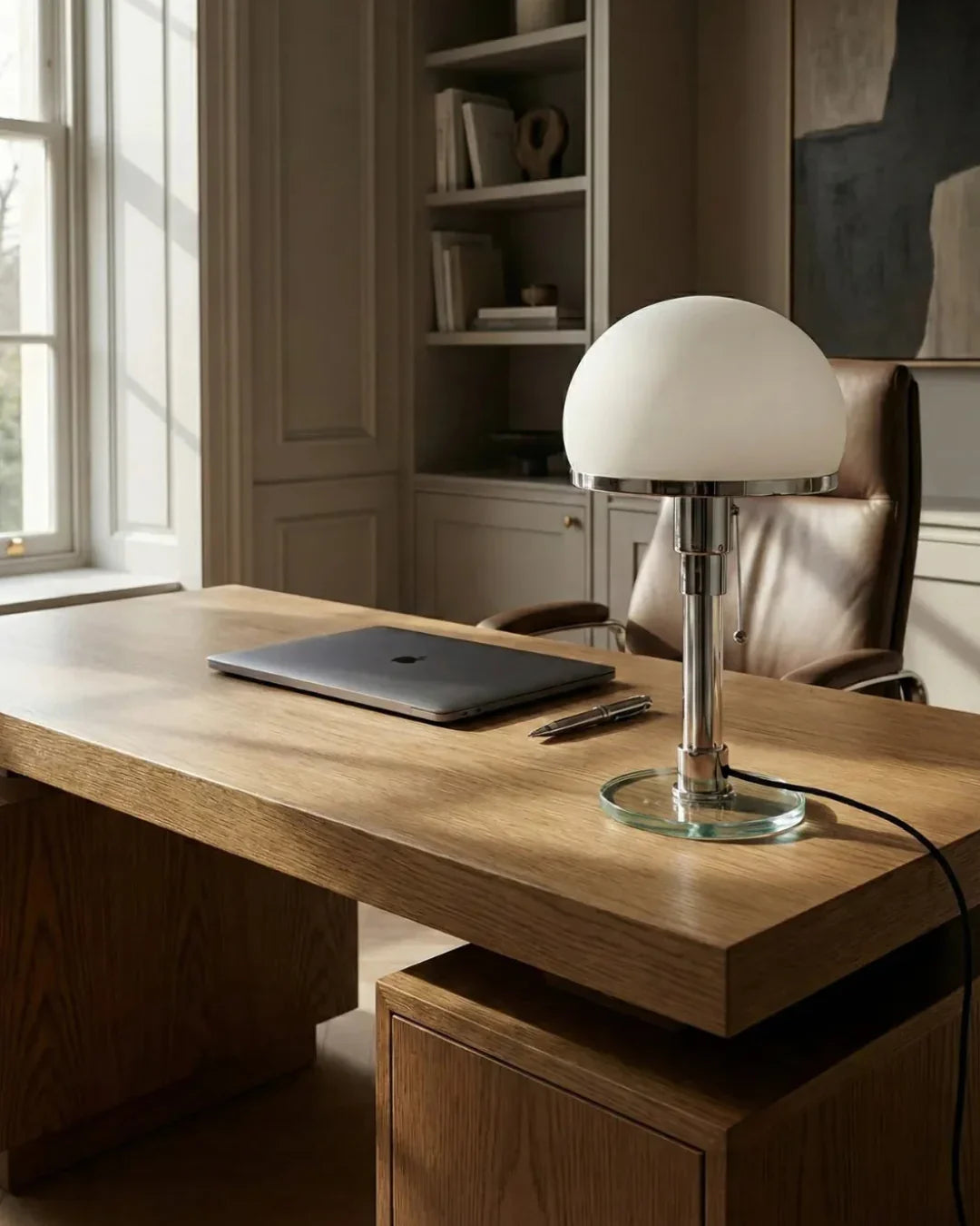 Opal globe table lamp LUMA No.01 on a wood desk with a laptop in front of built-in bookshelves