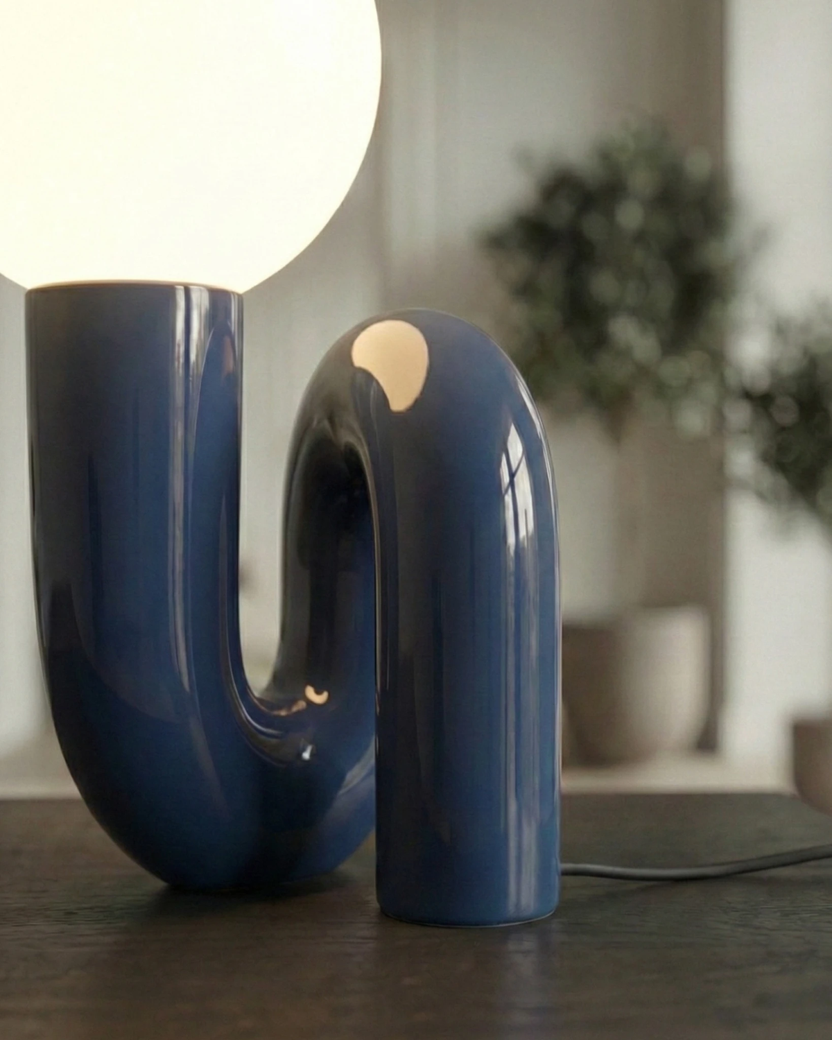 Close-up of the VICO No.01 opal globe table lamp in french blue, glossy curved resin with the globe lit