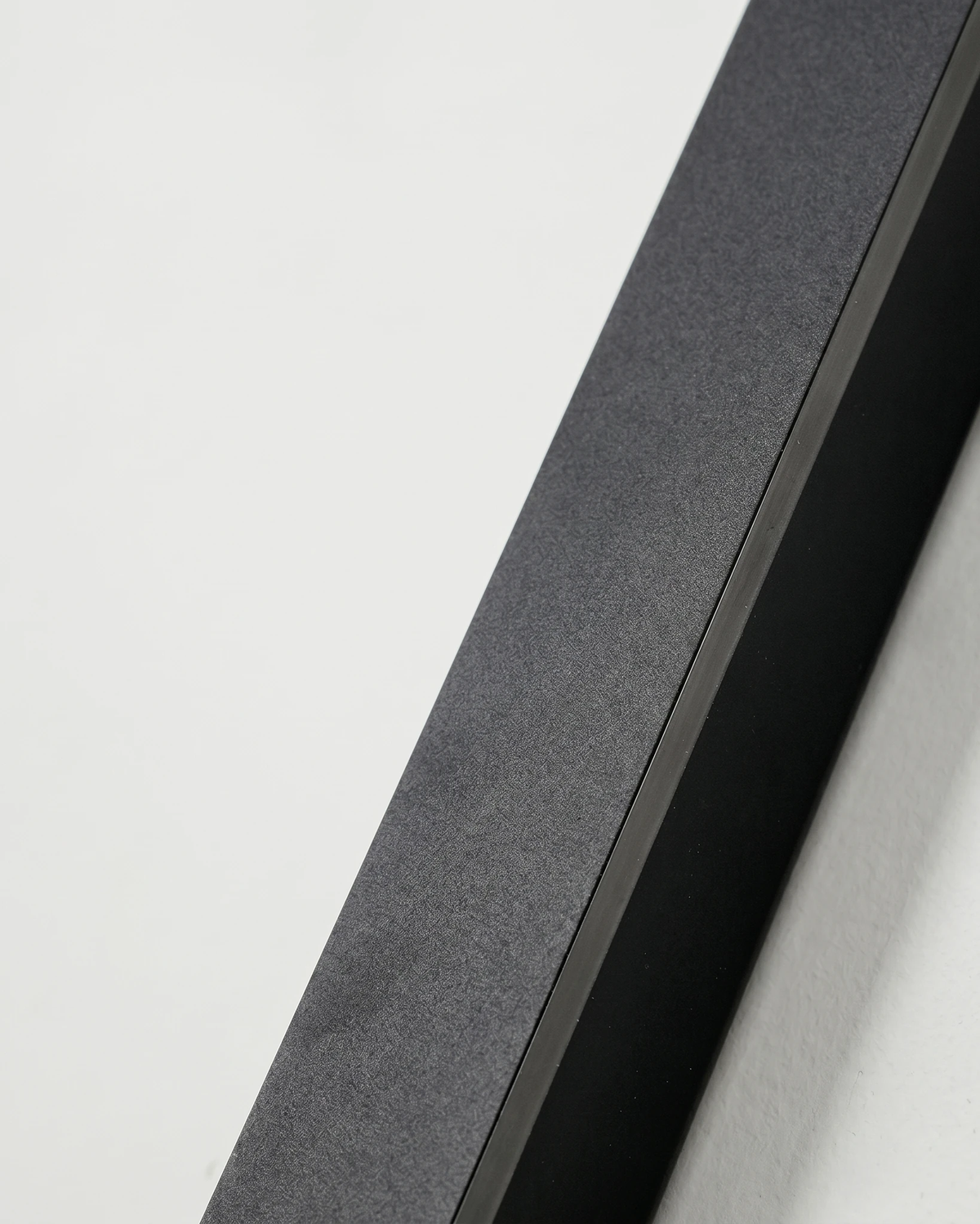 Close-up of the end of the black aluminum bar of the outdoor wall sconce FRECCIA No.01, thin LED edge switched on
