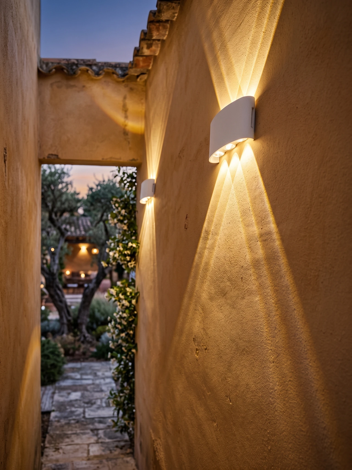 Outdoor wall sconce PALAZZO No.01 in matte white, two units lit on an ochre stucco wall along a garden passage