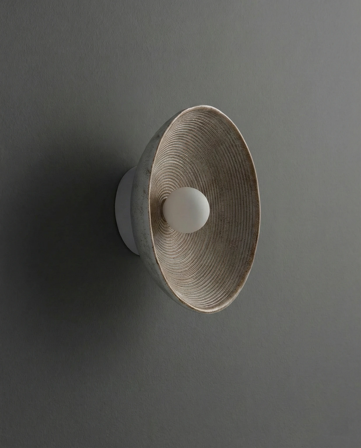 Stone-look wall sconce ECCO No.01 side view on a dark gray wall, ridged bowl with the pearl bulb off