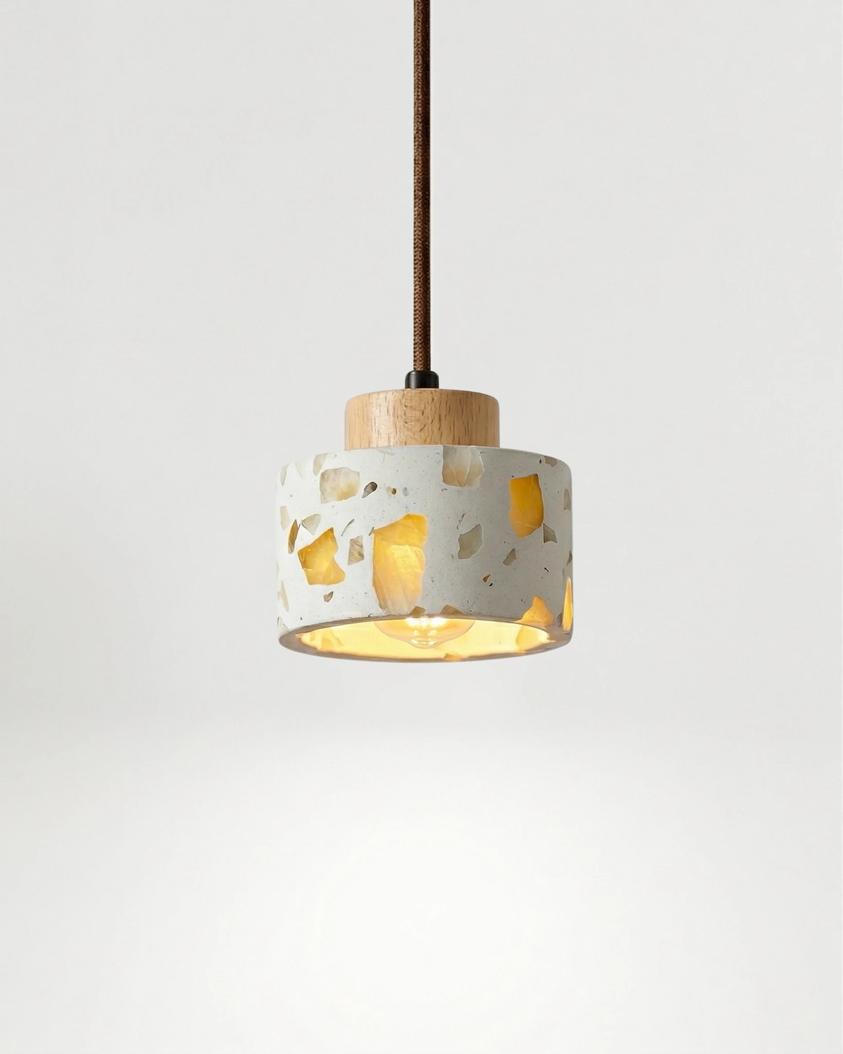 Terrazzo pendant light GROTTA No.01 drum with a light natural wood cap, wide flecked shade switched on