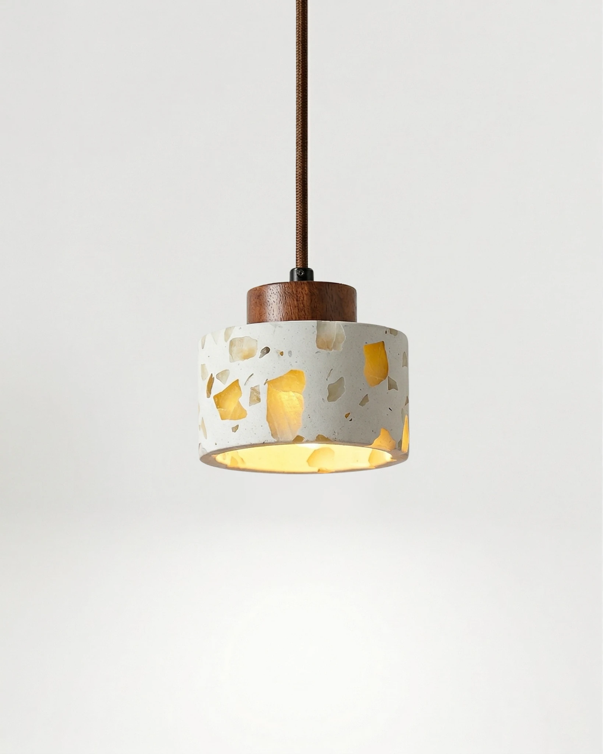 Terrazzo pendant light GROTTA No.01 drum with a dark walnut cap, wide gold-flecked shade switched on