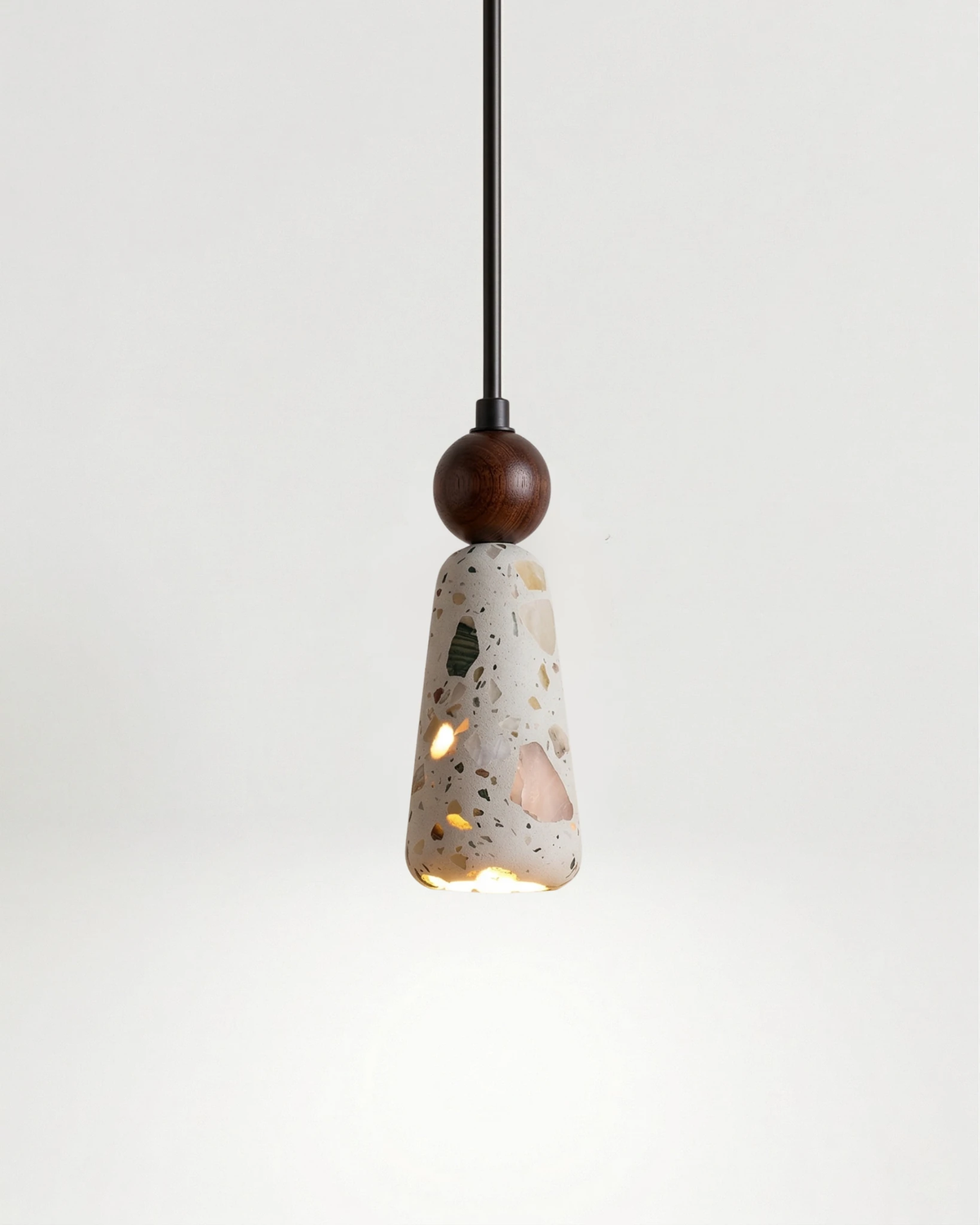 Terrazzo pendant light GROTTA No.01 totem, tapered cone under a walnut ball, switched on, white background