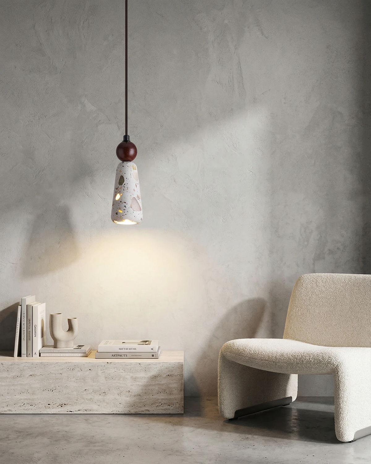 Terrazzo pendant light GROTTA No.01 totem with walnut ball, lit above a travertine block table and boucle chair