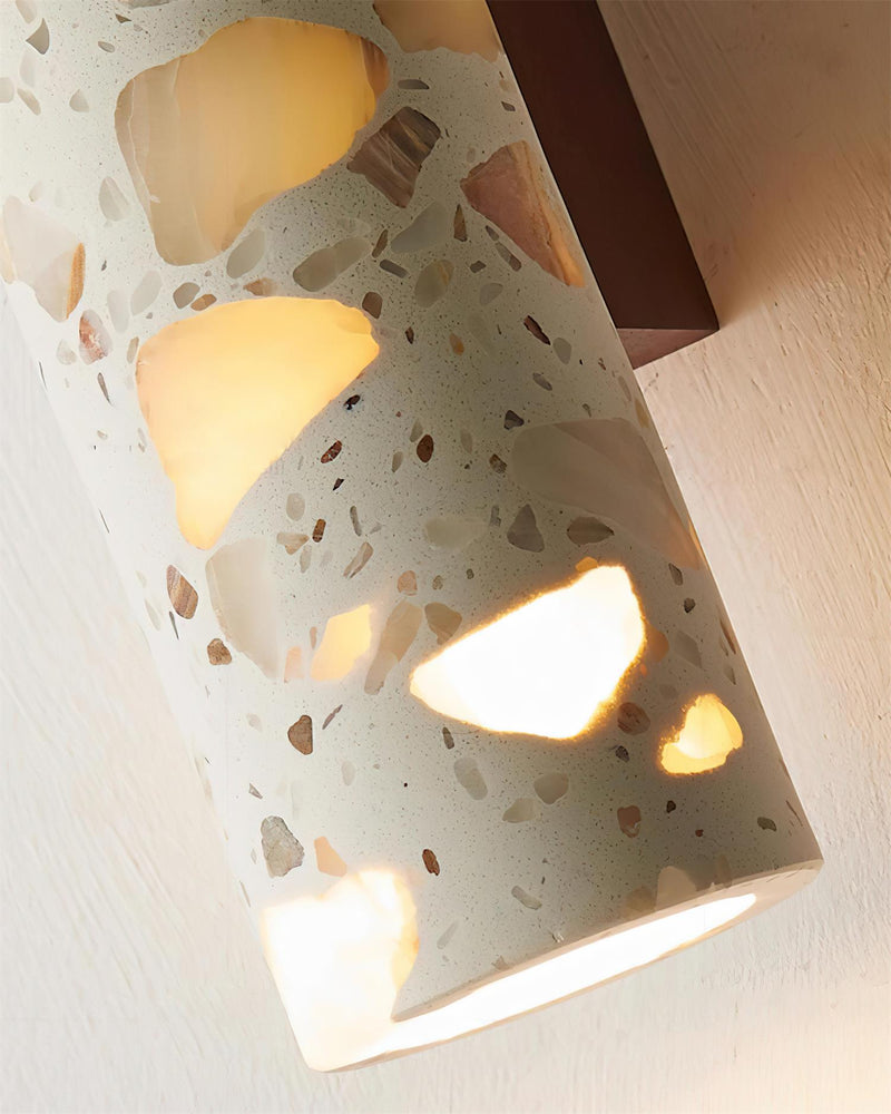 Close-up of the lit terrazzo wall sconce INCA No.02 with amber light glowing through the stone chips