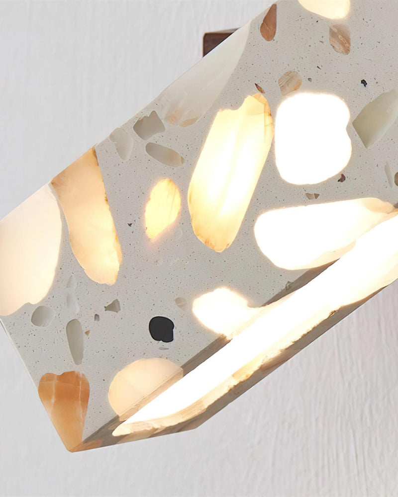 Close-up of the lit terrazzo wall sconce PIETRA No.07 with light glowing through the stone chips