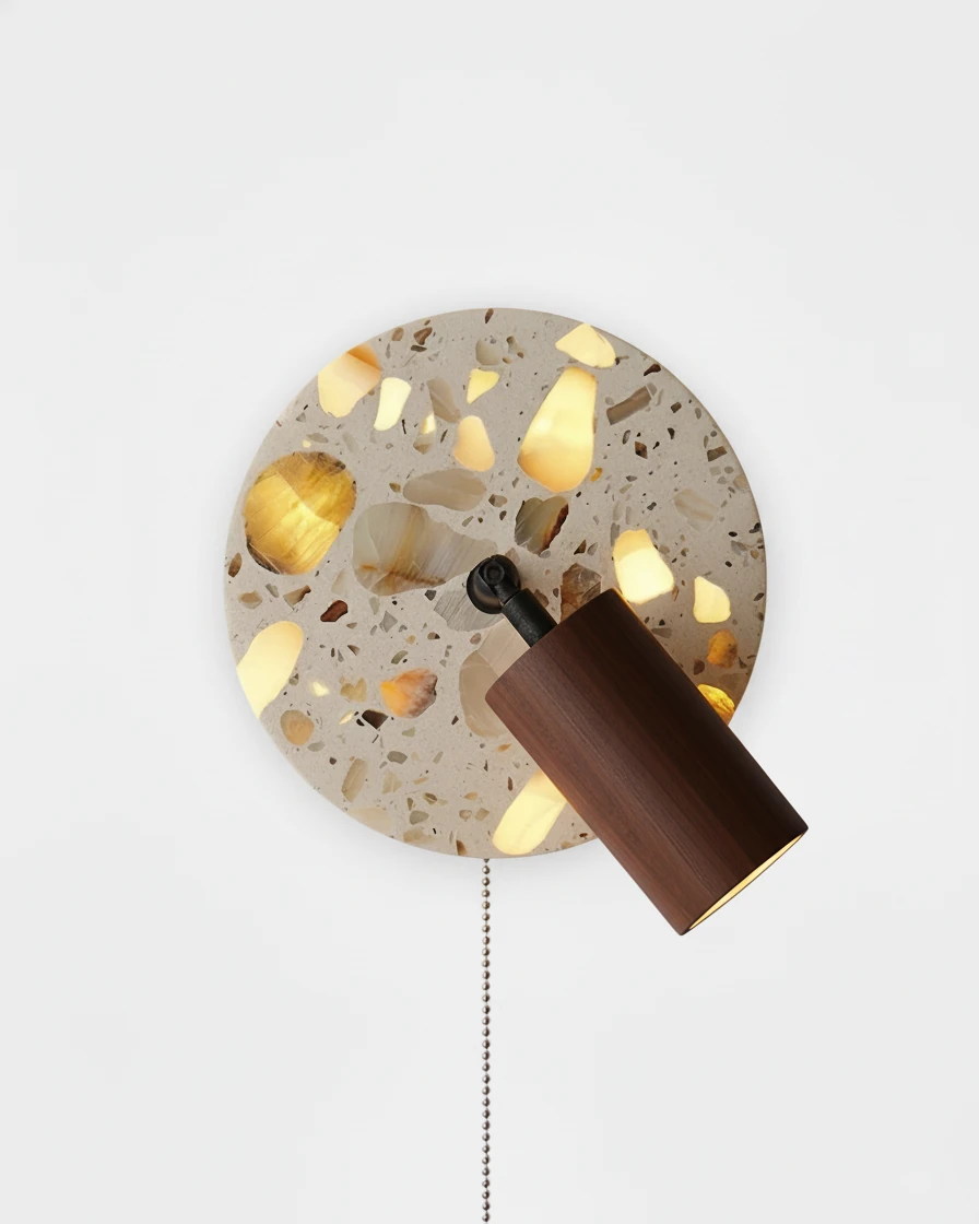 Terrazzo wall sconce PIETRA No.08 in Walnut, backlit terrazzo disc with glowing chips and a walnut spot, pull chain