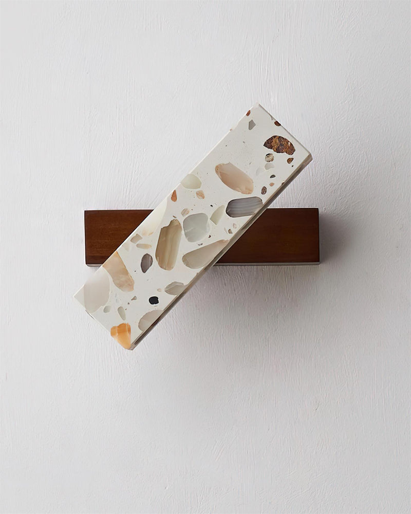 Terrazzo wall sconce PIETRA No.07 unlit, angled terrazzo bar on a walnut base against a white wall