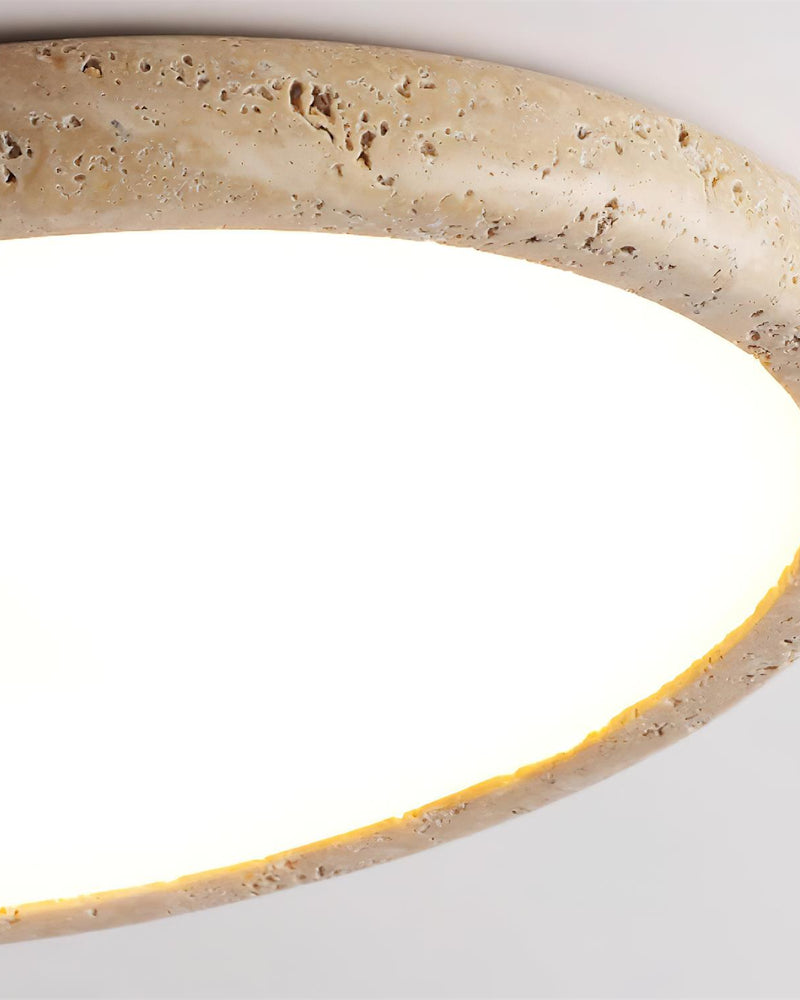 Close-up of the pitted travertine edge of the LUNA No.05 travertine flush mount ceiling light, glowing