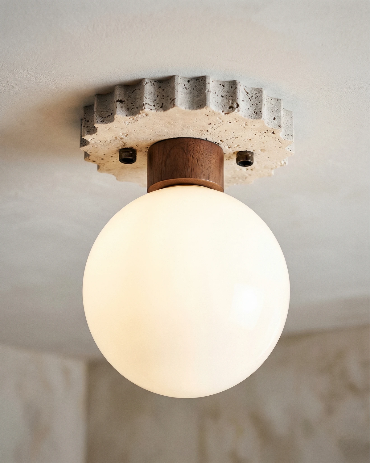 Close-up of the lit opal globe and scalloped travertine canopy of the LUNA No.07 travertine flush mount ceiling light